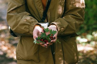 Midsection of woman berry fruits while standing on land