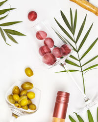 Wine glasses with grapes and green olives, bottle of rose wine and palm leaves