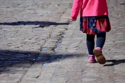 Low section of child walking on cobblestone