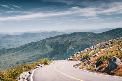 Scenic view of road by mountains against sky