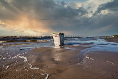 Lighthouse by sea against sky during sunset after storm 