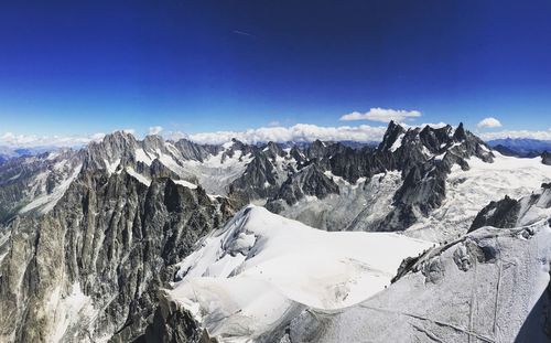 Scenic view of snowcapped mountains against blue sky