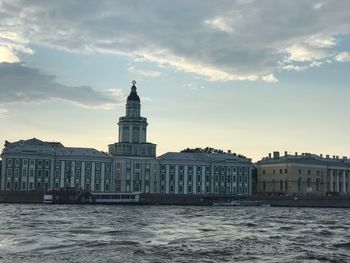 View of buildings at waterfront against cloudy sky