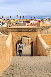 Rear view of man walking in front of building