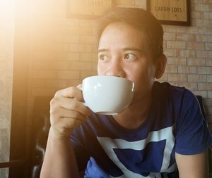 Man looking away having coffee while sitting at table in caf�