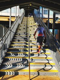 Rear view of man walking on footbridge