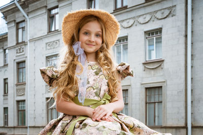 Little girl in dress and hat posing on the balcony