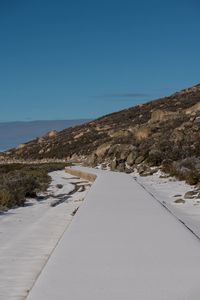 Road by mountain against clear blue sky