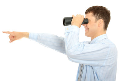 Side view of young man holding camera against white background