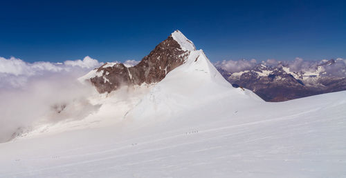 Scenic view of snowcapped mountains against blue sky