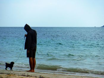 Dog standing on beach against clear sky