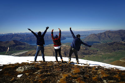 Rear view of men standing on mountain against sky