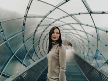 Portrait of woman standing against railing