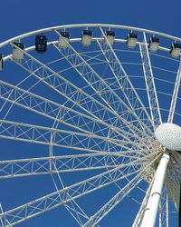 Low angle view of ferris wheel against blue sky