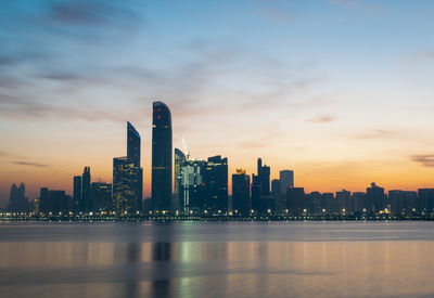 Illuminated buildings against sky during sunset