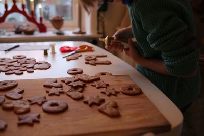 Midsection of girl decorating gingerbread cookies on table