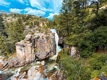 Scenic view of river flowing through rocks in forest