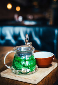 Close-up of mint tea in jar by cup on table