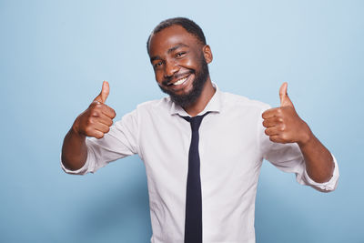 Portrait of young man gesturing against blue background