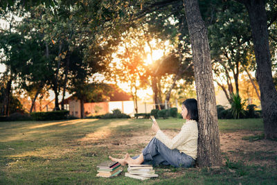 Side view of woman sitting on book in park