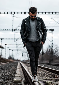 Young man walking on railroad track