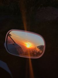 Close-up of side-view mirror against clear sky at sunset