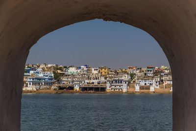 View of sea by buildings against clear sky