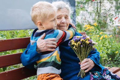 Grandson boy giving a flower to grandma. grandson and grandmother spending time together. granny