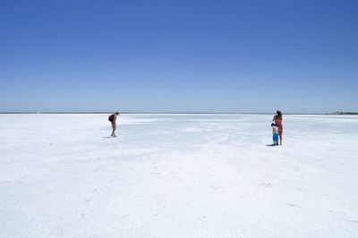 Tourist standing on dry salt lake against clear sky