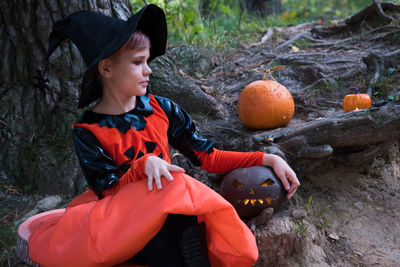 Girl looking away while standing by pumpkins