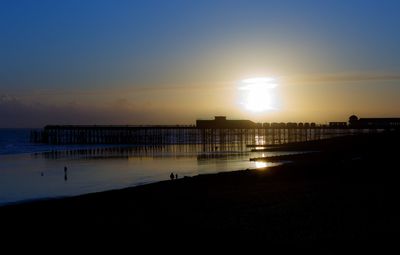 Silhouette pier over sea against sky during sunset