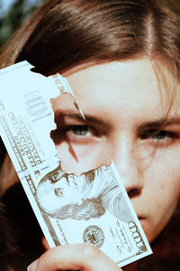 Close-up portrait of teenage girl with burned money