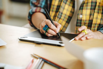 Young illustrator using graphic tablet at desk in office