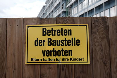 Text on wooden fence against building