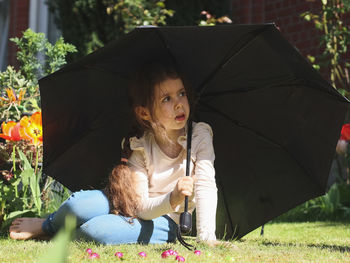 Caucasian girl with an umbrella on the lawn.