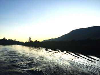 Scenic view of silhouette mountains against clear sky during sunset