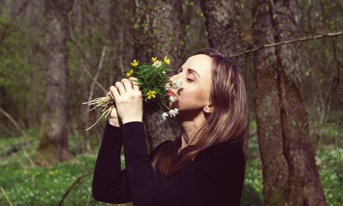 Woman holding flower in forest
