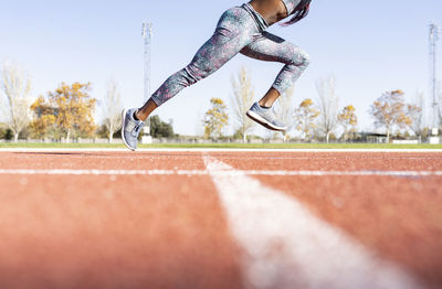 Female sportsperson running on sports track during sunny day