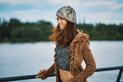 Woman standing by railing against lake