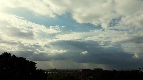 Silhouette of city against cloudy sky