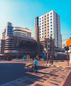 People working on city street by buildings against sky