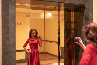 Happy woman taking photograph in mirror