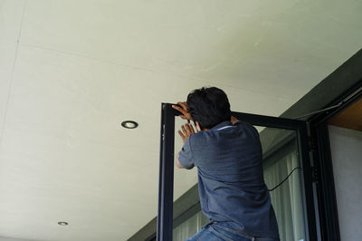 Rear view of young man leaning against wall