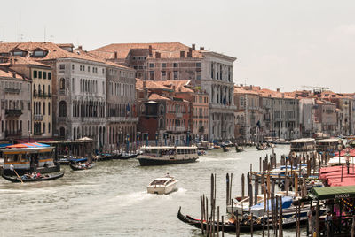 Sailboats moored on canal by buildings against clear sky