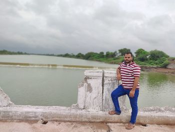 Full length portrait of smiling standing on lake against sky