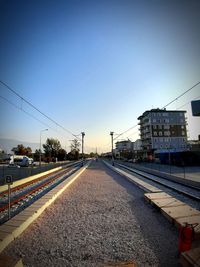 Railroad tracks in city against clear blue sky