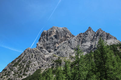 Low angle view of rocky mountains against clear blue sky