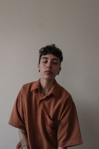 Portrait of young woman standing against wall