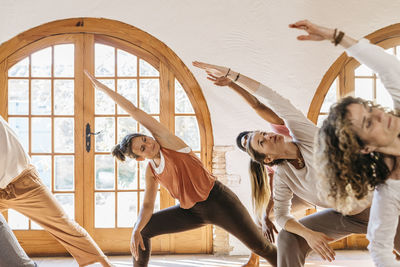 Instructor and students stretching hands in yoga studio