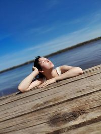 Woman lying on wood against sky